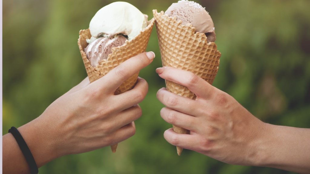 two hands each holding an ice cream cone