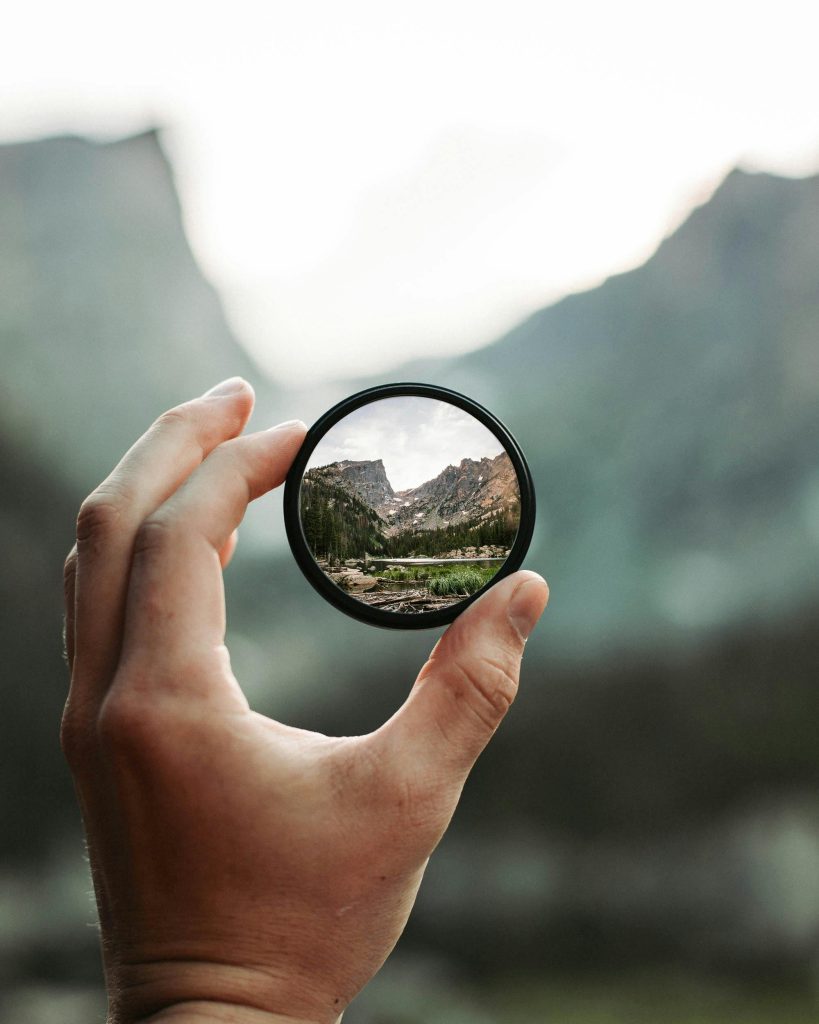 Hand holding a camera lens filter focused symbolizing clarity and perspective.
